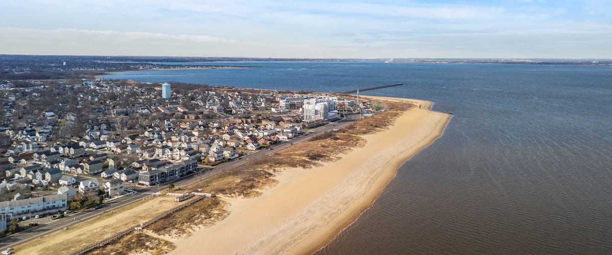 A coastal town with a beach, a large water body, and industrial structures.