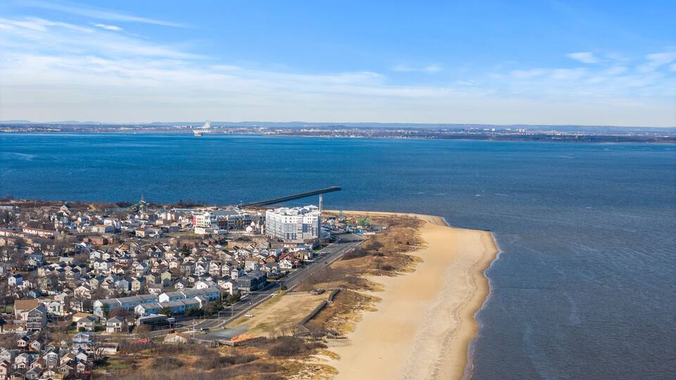 A coastal town with a large industrial building, a sandy beach, and a calm sea.