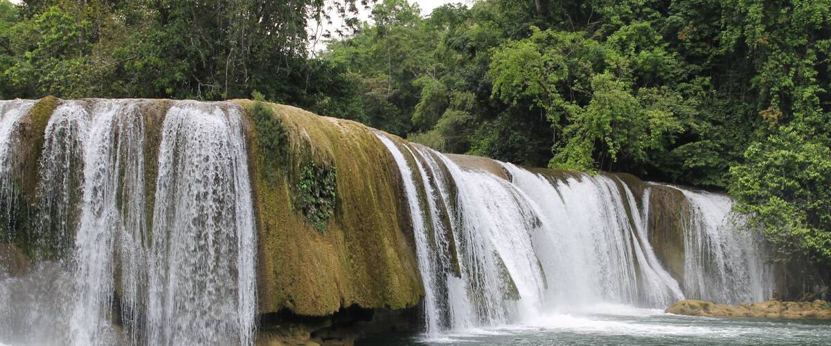 A multi-tiered waterfall surrounded by lush greenery.