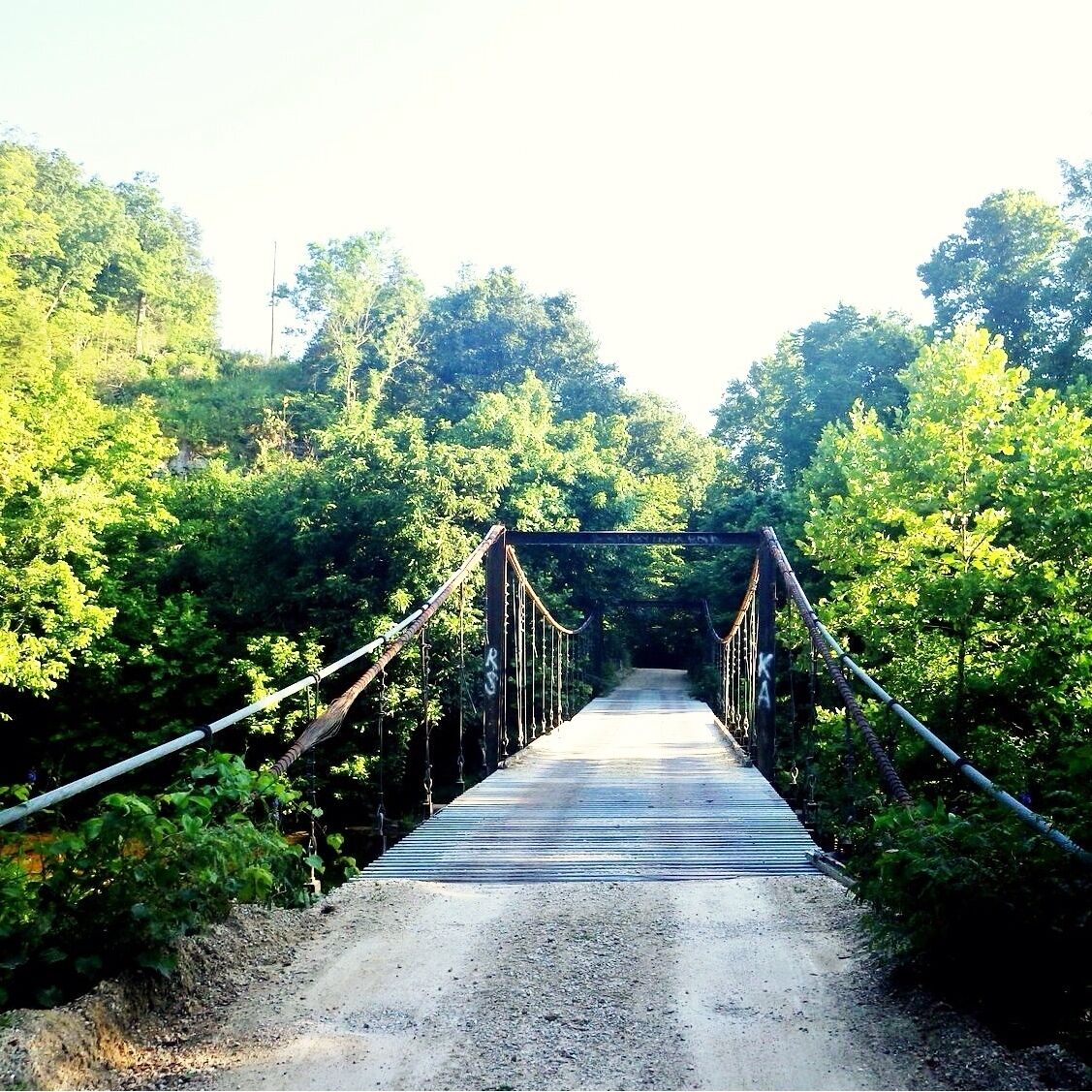 These bridges were first built when existing low water bridges were covered by water. The great advantage of the swinging bridge design was that it could span a very wide river without needing foundation pillars in the middle. This meant that there was no obstruction to river traffic during construction and no danger of the pier being damaged during floods. They were also cheaper to build than pier designs.
The upright piers were constructed first before being pulled into position by mules. The cable was then dragged across by hand using a wheel or pulley. The Swinging Bridges were built during The Great Depression and took only 3 months to complete. Of all the many swinging bridges built in the area during that era, the two Swinging Bridges crossing the Grand Glaize Creek at Brumley, are the only swinging bridges left standing. Although the smaller bridge has undergone some reconstruction, they are both still usable by the public.
The Swinging Bridges span a small river in an area of stunning natural beauty and many visitors enjoy fishing and camping during the summer months. The water temperatures are usually warm as the river is very shallow, so it is ideal for day trips of picnicking on the shore followed by a gentle swim.
