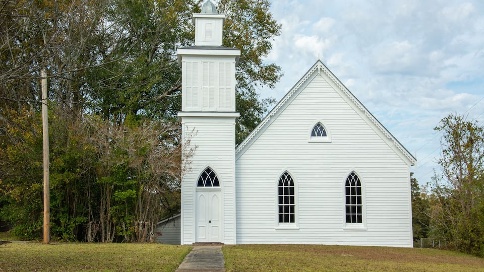 A white church with a steeple and two arched windows.