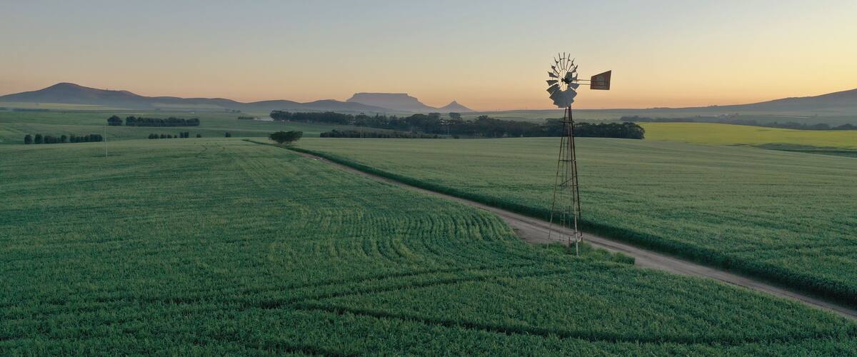 A windmill in a green field with distant hills.