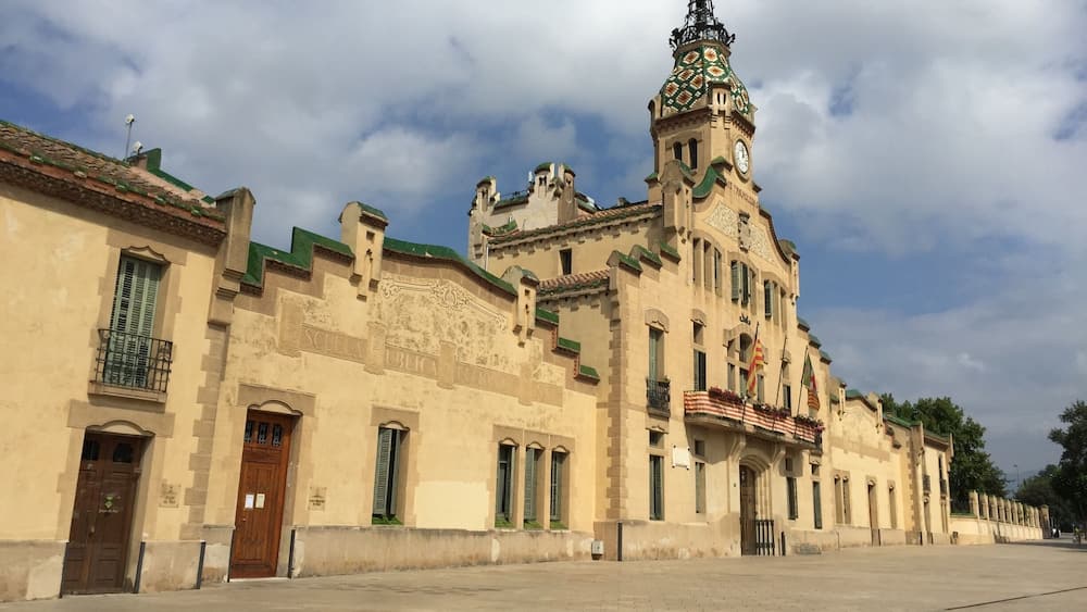 Ein historisches Gebäude mit einem Glockenturm, grünen Fensterläden und einem Ziegeldach.