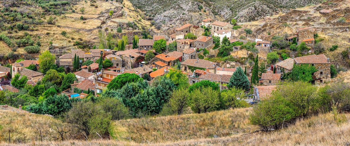 A hillside village with stone houses and terraced fields.