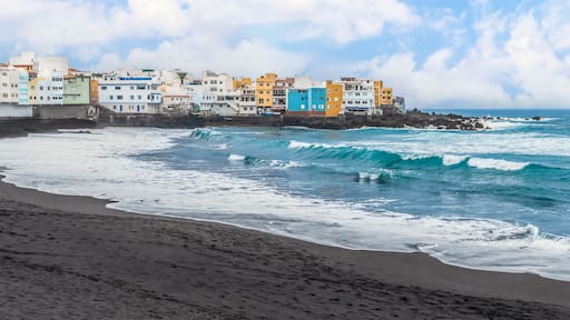 Wave crests with white foam on the surface of the turquoise water of the Atlantic Ocean on Playa Grande beach in Puerto de la Cruz, Spain. Amazing seascape of a beach with volcanic black sand