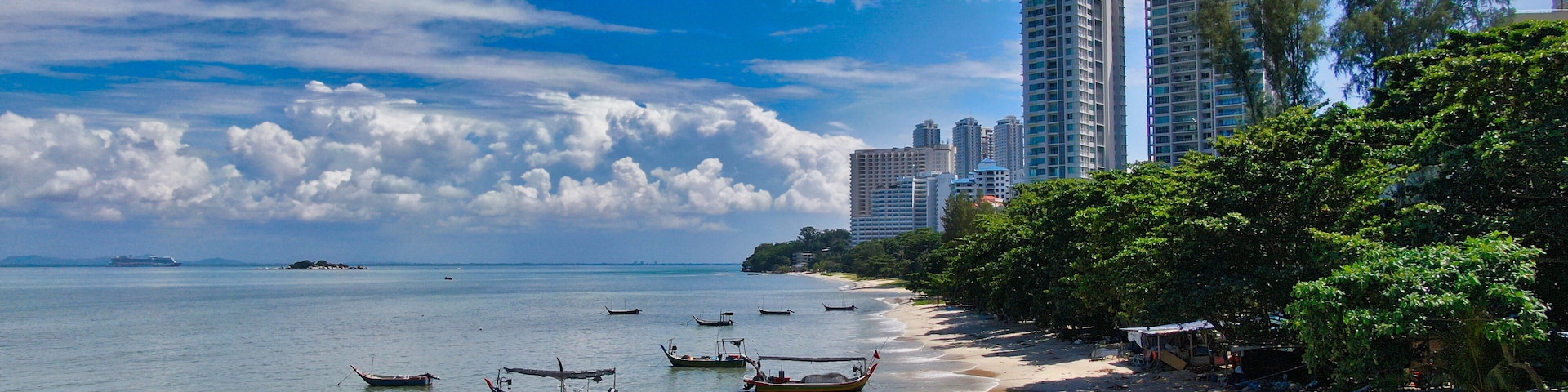 A beach with boats, a sandy shore, and tall buildings in the background.