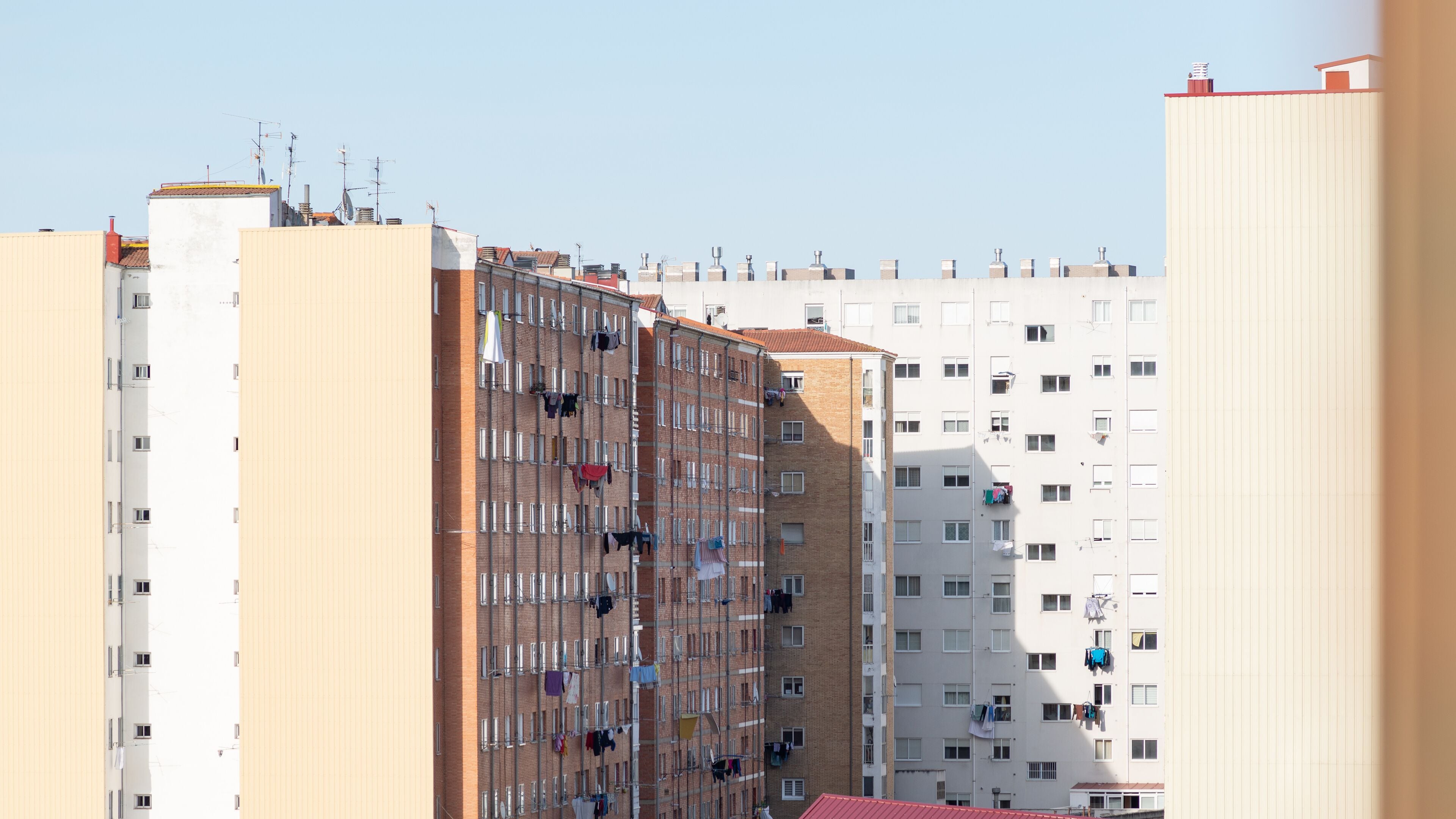 A row of multi-story residential buildings with balconies, some with laundry hanging out to dry.