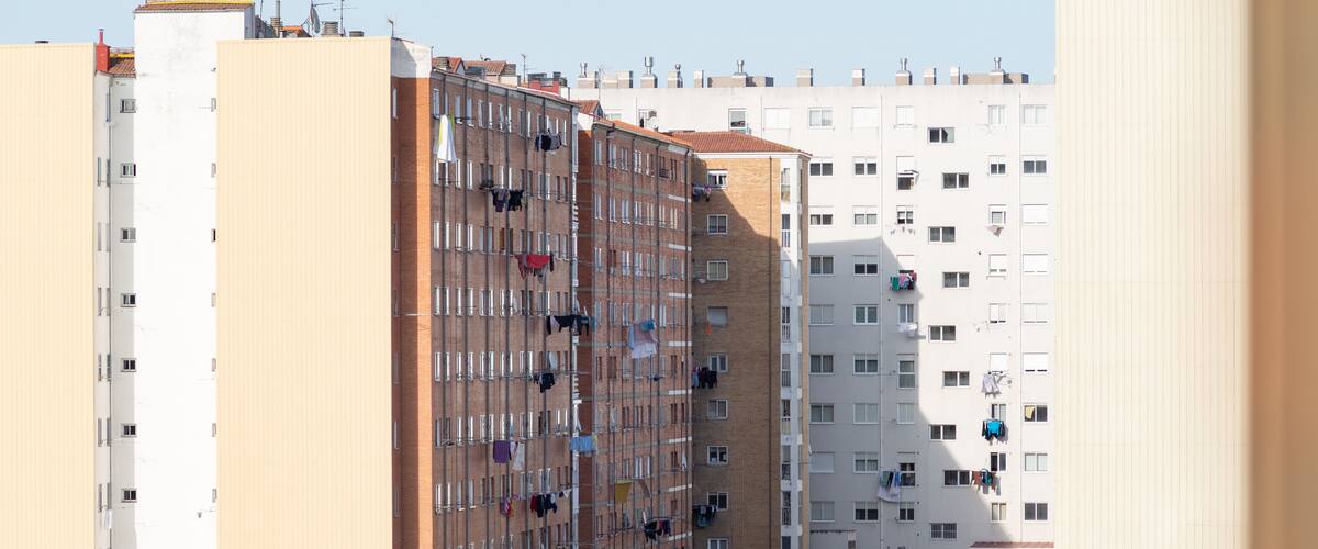 A row of multi-story residential buildings with balconies, some with laundry hanging out to dry.