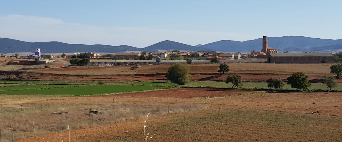 A rural landscape with fields, a water tower, and a church with a bell tower.