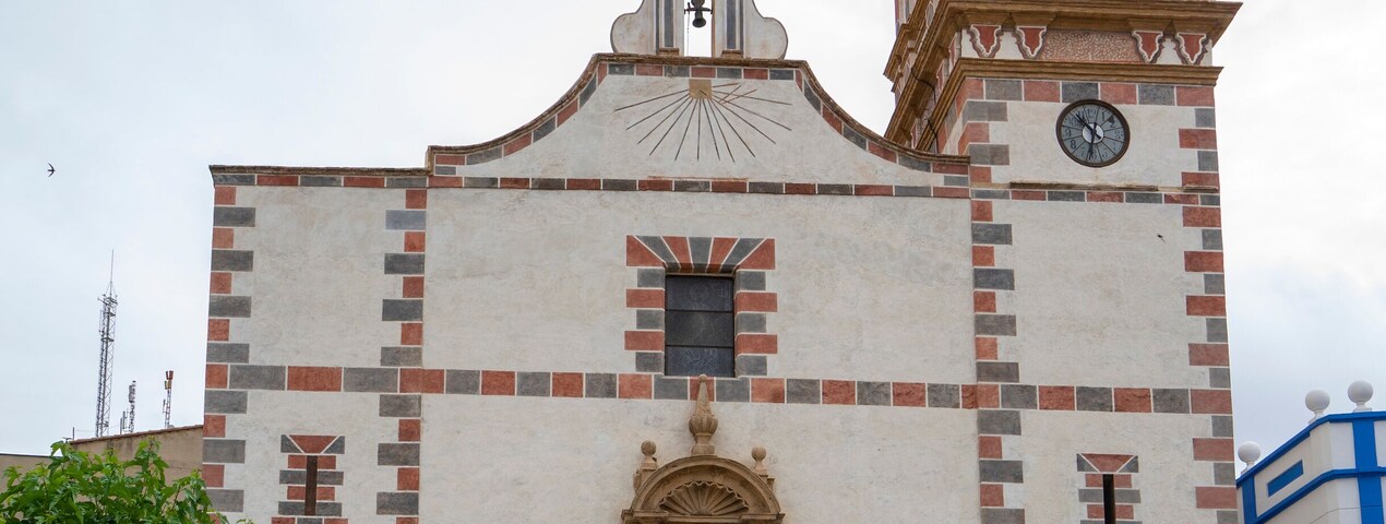 Una iglesia histórica con un campanario, un reloj y una estatua en primer plano.