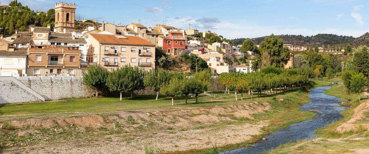 A river flowing through a town with historic buildings and a prominent tower.