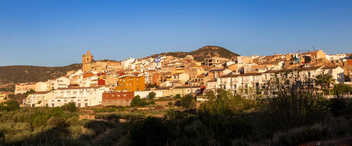 A coastal town with a prominent church on a hill, surrounded by colorful buildings and a clear blue sky.