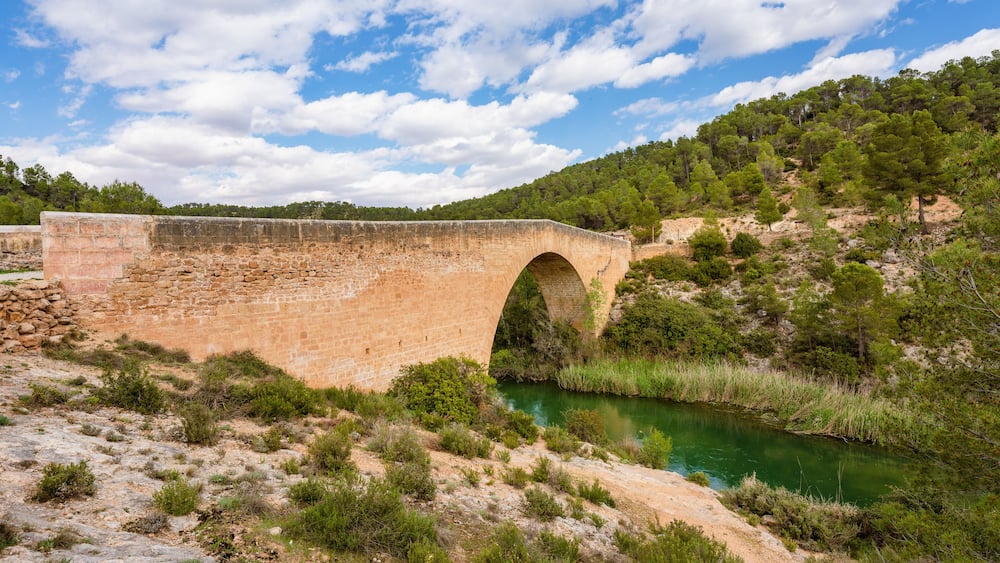 Antique one arch stone bridge over a river the Hoces del Rio Cabriel Natural Park between Valencia and Cuenca in Spain. Protected Area.