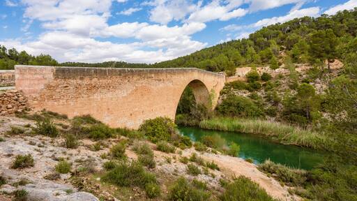 Antique one arch stone bridge over a river the Hoces del Rio Cabriel Natural Park between Valencia and Cuenca in Spain. Protected Area.