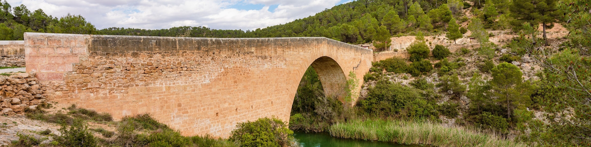 Antique one arch stone bridge over a river the Hoces del Rio Cabriel Natural Park between Valencia and Cuenca in Spain. Protected Area.