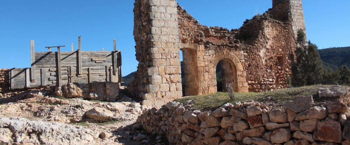 A historical stone structure with arches and a wooden fence.