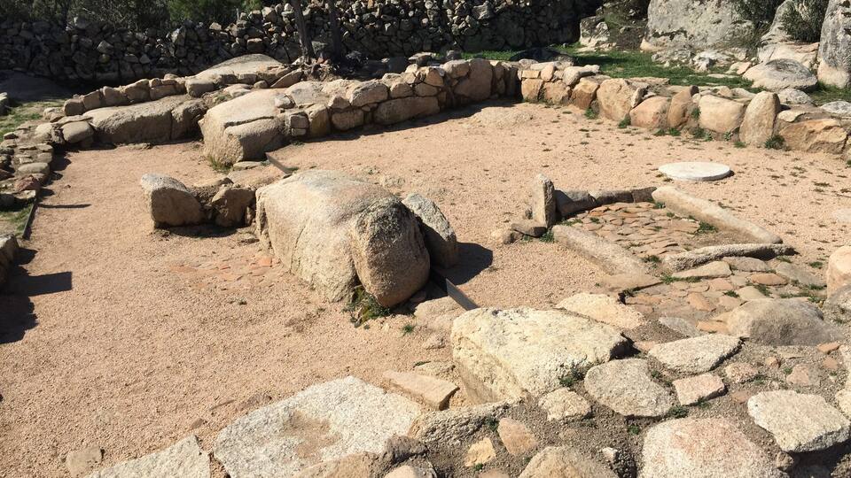 Ancient ruins with stone walls and scattered stones.