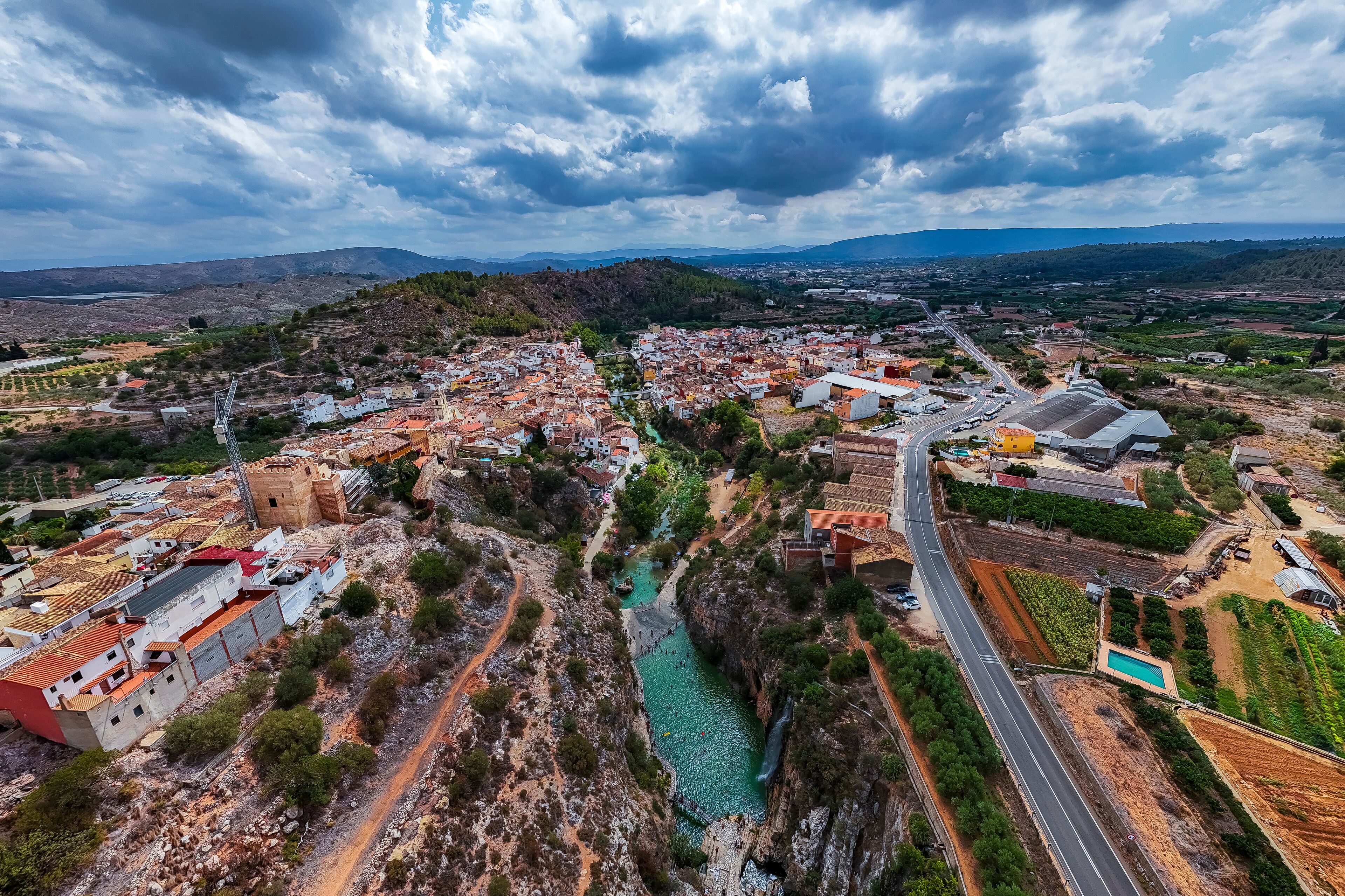 A town with a river, roads, and surrounding hills.