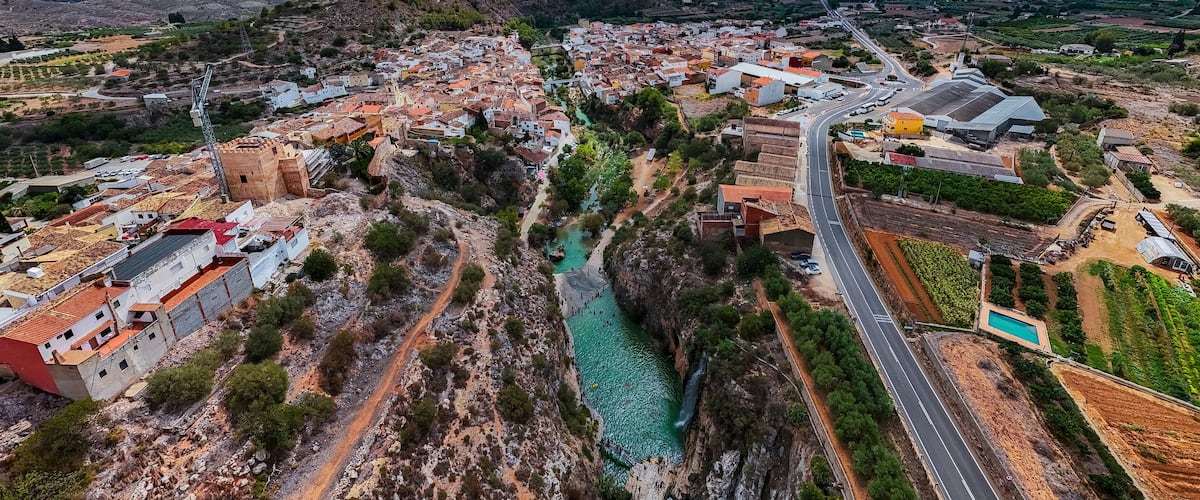 A town with a river, roads, and surrounding hills.
