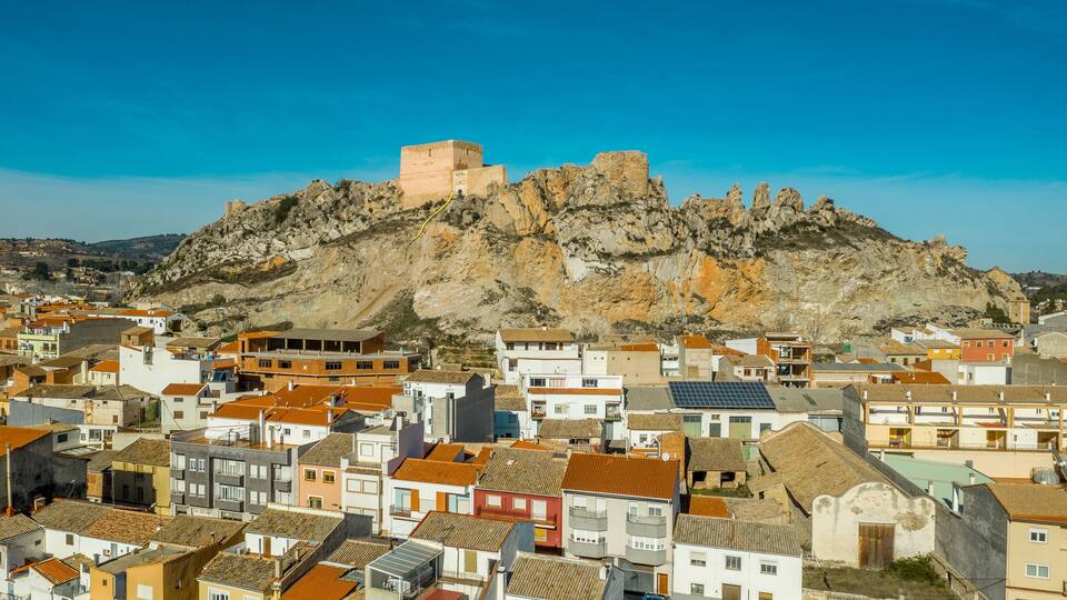 A coastal town with colorful buildings and a historic fort on a rocky hill.