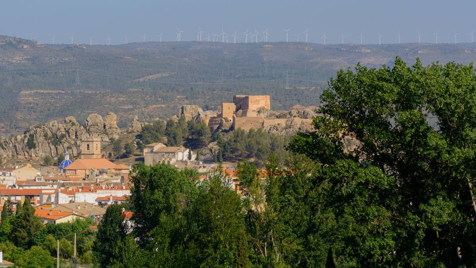 A town with historic buildings and wind turbines in the background.