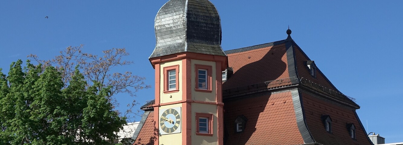 A historic building with a prominent tower, a clock, and a red roof.