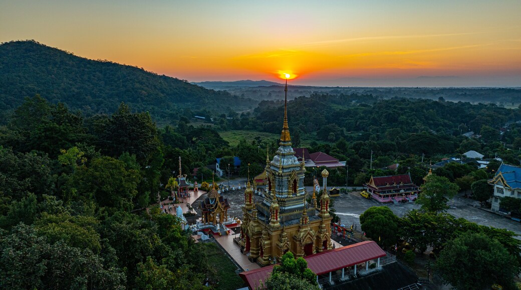 Aerial view of Mae Klang Waterfall Temple in Chiang Mai with the sunrise casting warm hues in calm sky. The tranquil setting highlights the serene beauty of the temple and the natural landscape.