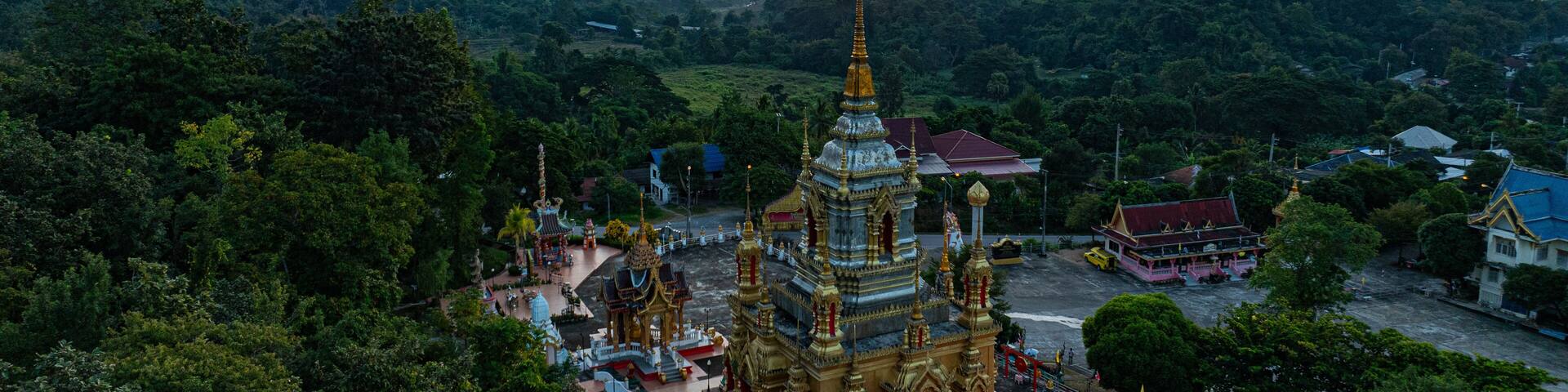 Aerial view of Mae Klang Waterfall Temple in Chiang Mai with the sunrise casting warm hues in calm sky. The tranquil setting highlights the serene beauty of the temple and the natural landscape.