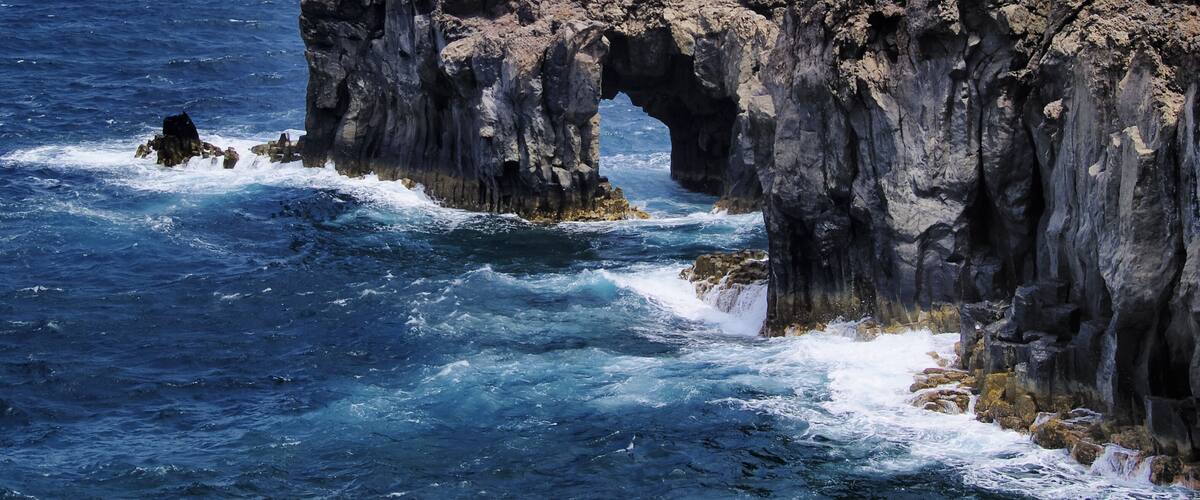 A rugged coastline with a prominent rock arch formation.