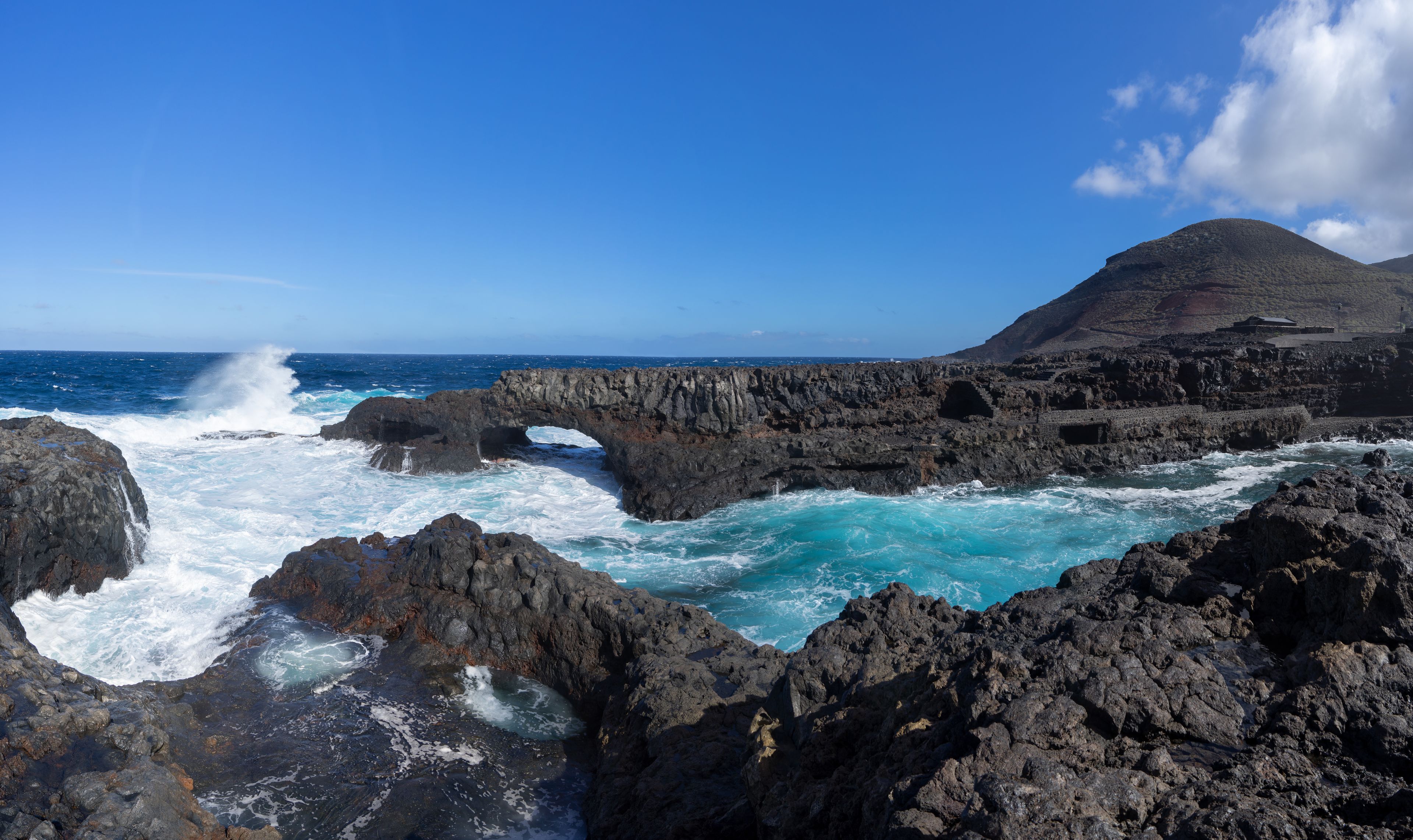 El Hierro, Kanarische Inseln - Küste mit Felsbogen an der Badebucht Charco Manso nahe Echedo, rechts der Berg Montana de las Salinas