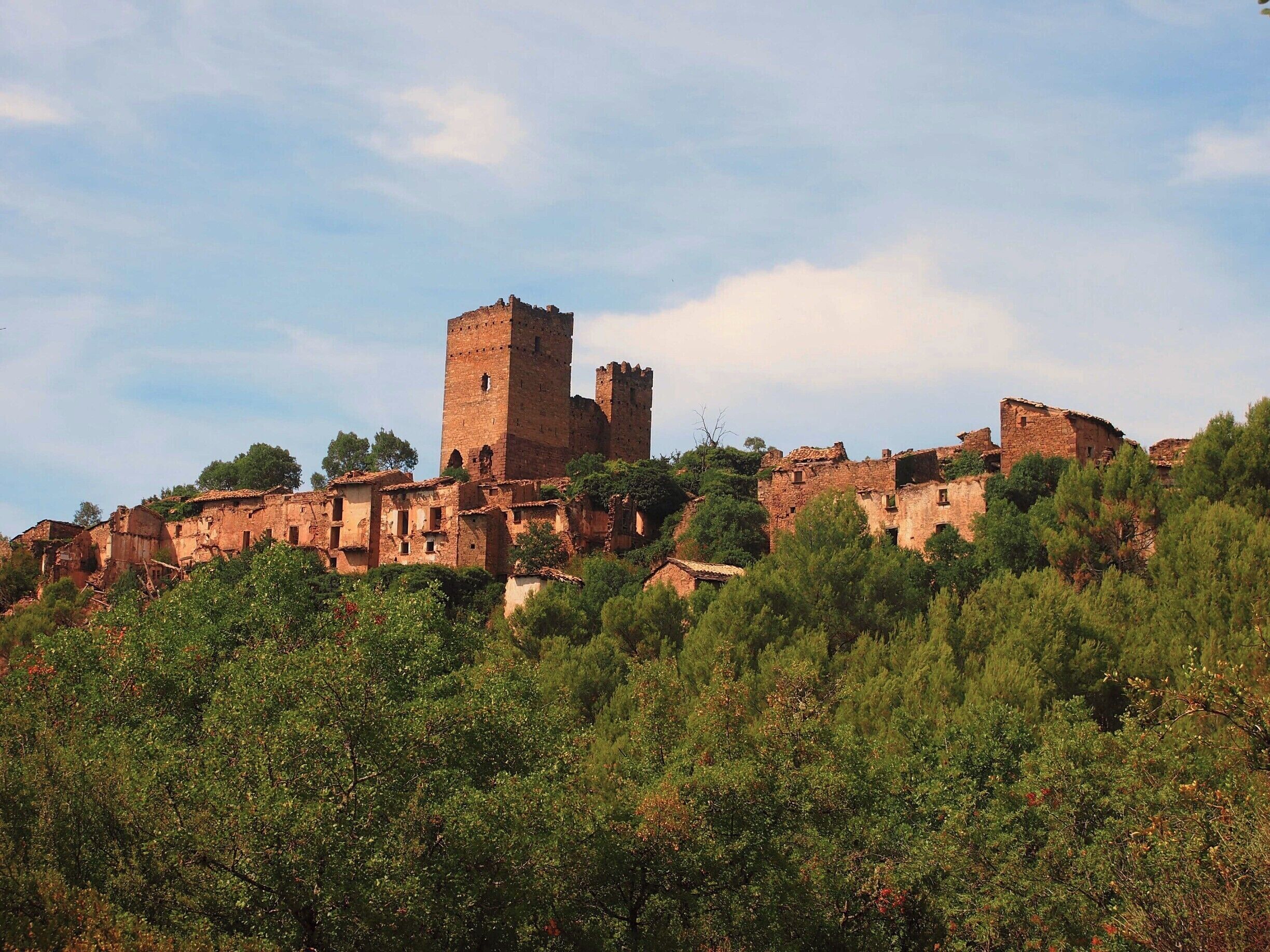 A historic hilltop town with ancient stone buildings and a prominent tower.