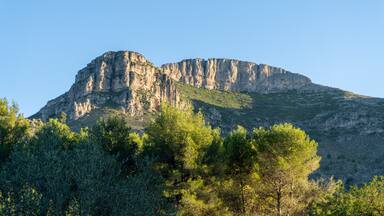 A mountain with rocky cliffs and green vegetation.