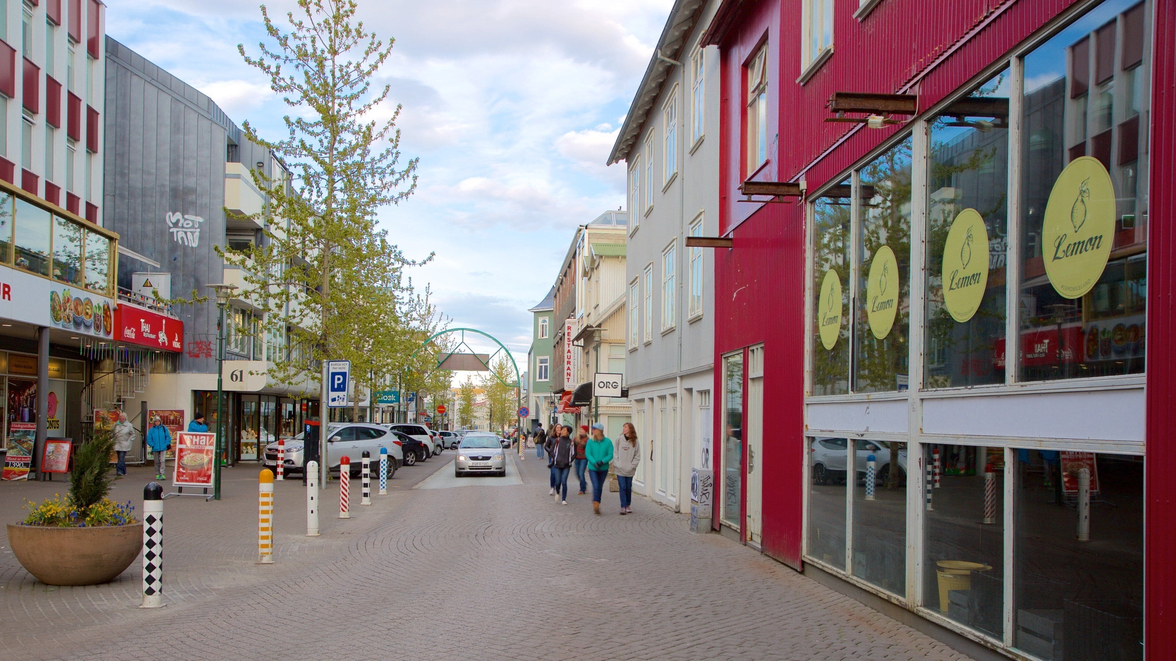 Une rue pavée bordée de boutiques, dont un restaurant thaïlandais et un magasin dont l’enseigne est jaune citron.