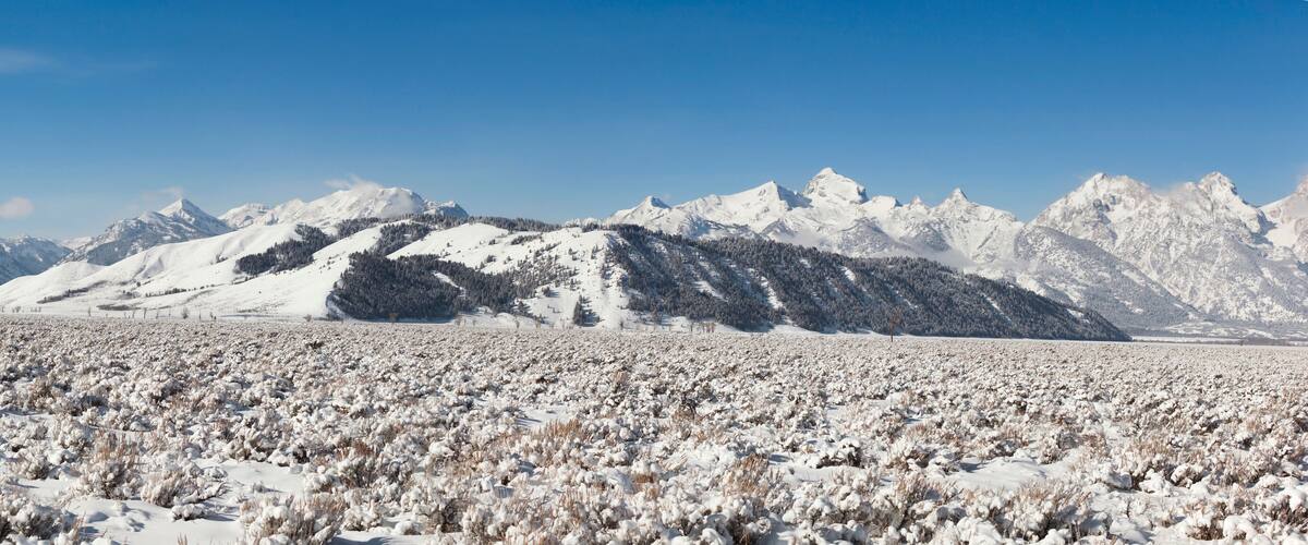 A snow-covered field with mountains in the background.