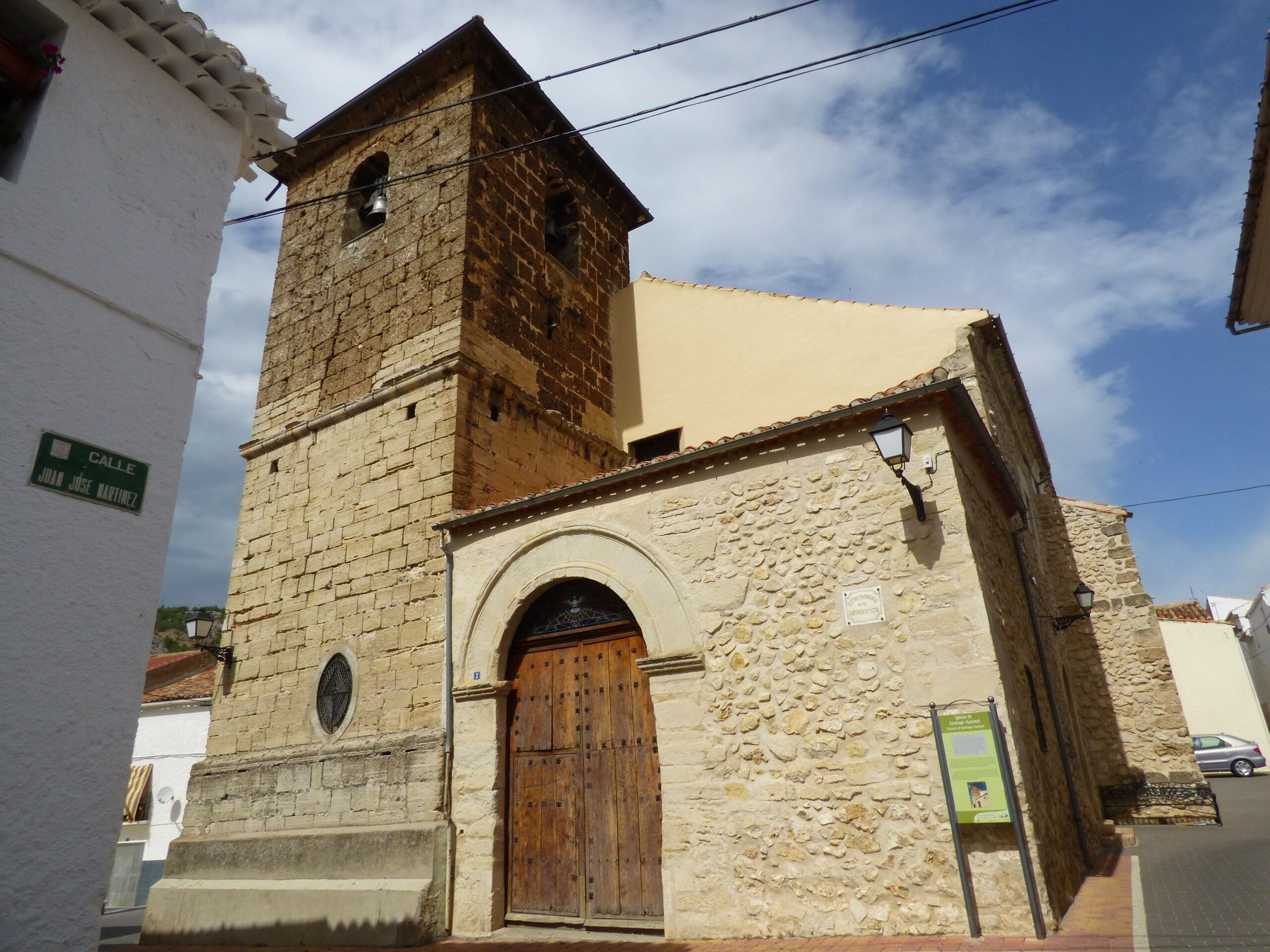 A historic church with a bell tower, a wooden door, and a sign reading "Calle Juan Jose Martinez".