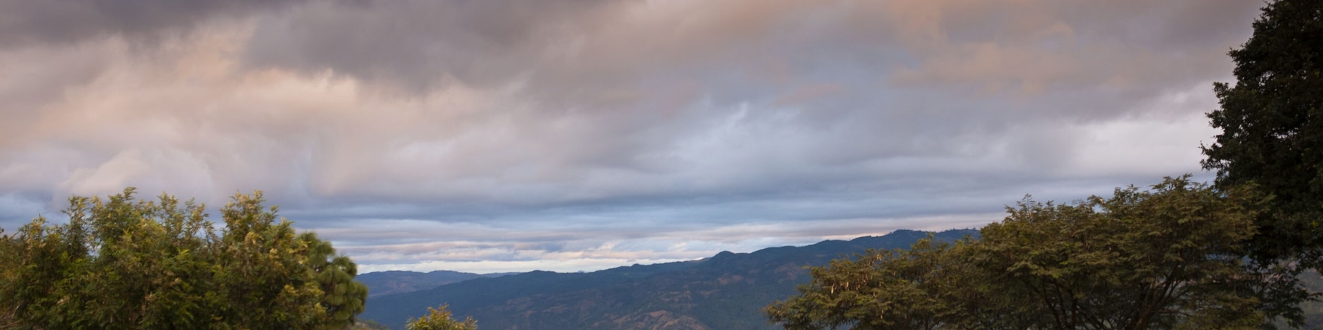 Un paisaje montañoso con vegetación densa y un cielo nublado.