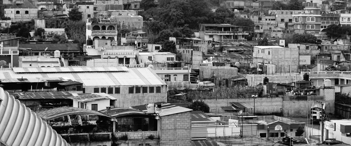 A densely packed urban area with numerous buildings, some with flat roofs and others with sloped roofs.