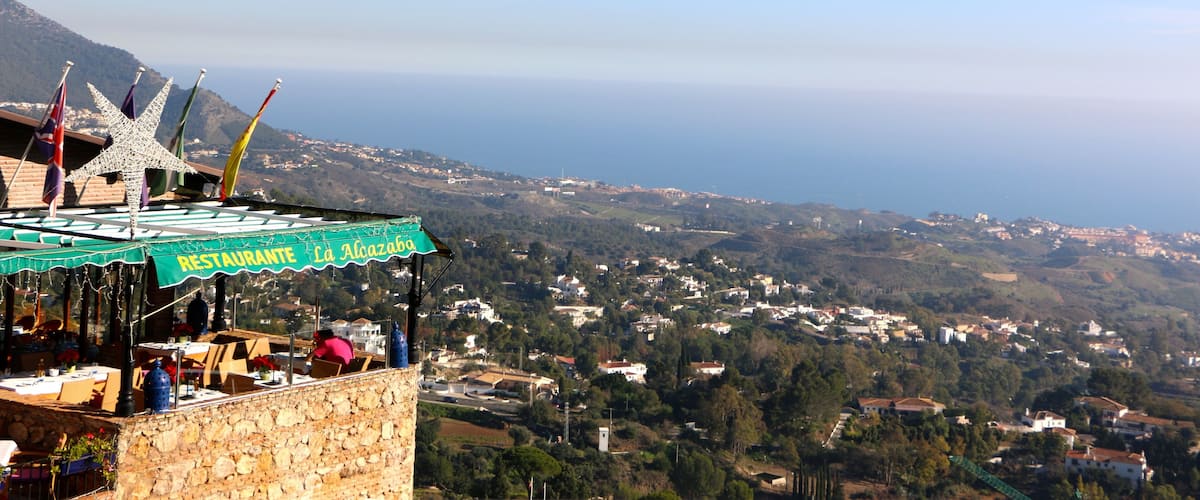 A restaurant named Restaurante La Alojazal overlooking a coastal town with houses and greenery.