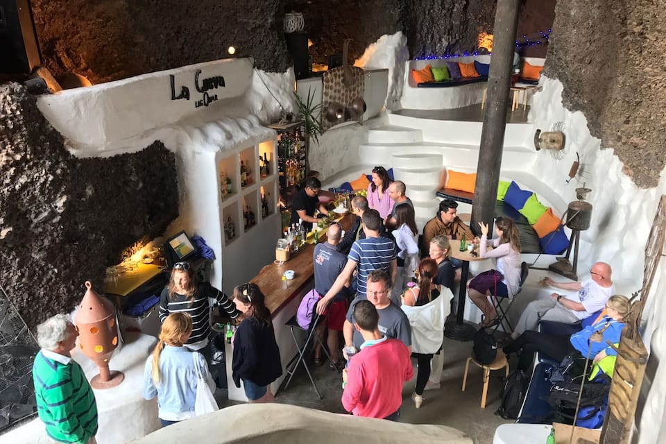 Een bar in een grot met een rustiek interieur, een bar en een zithoek met kussens.
