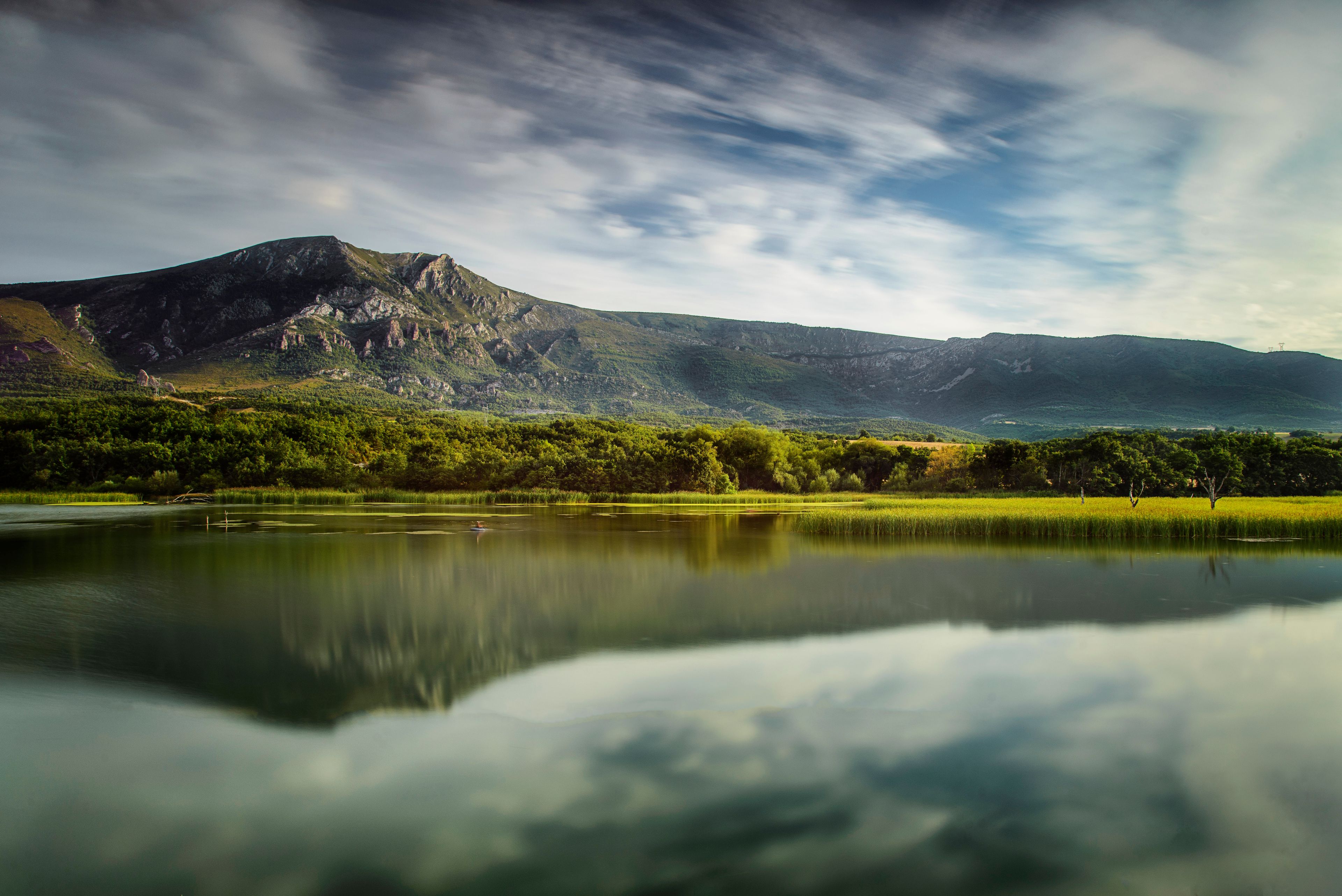 Scenic landscape of Sobron reservoir featuring mountain reflections in the calm water with green forests and a dramatic sky in northern Spain