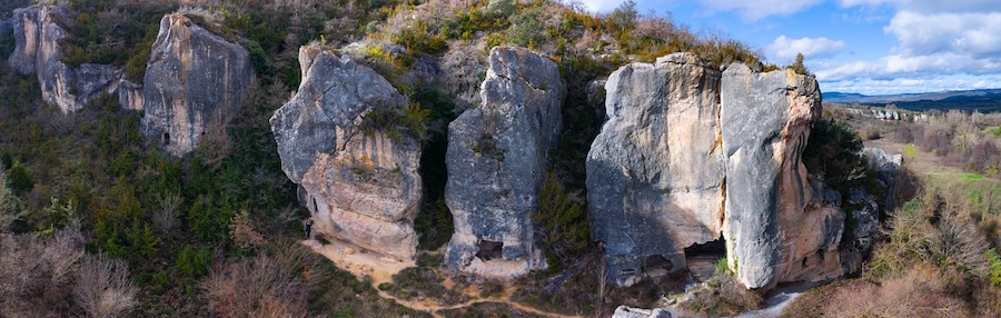 Un paisaje agreste con formaciones rocosas destacadas y un sendero estrecho que serpentea por una zona boscosa.