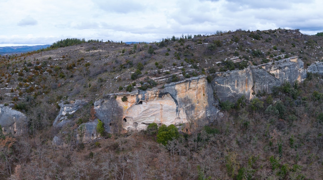 Un paysage montagneux accidenté, dominé par une formation rocheuse remarquable, qui présente une entrée de grotte.