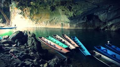 A cave with boats docked at the water's edge.