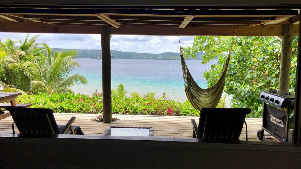 A hammock overlooking a tropical beach with a view of the ocean and distant islands.