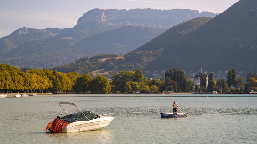Un lago con barcos, una persona remando y montañas al fondo.