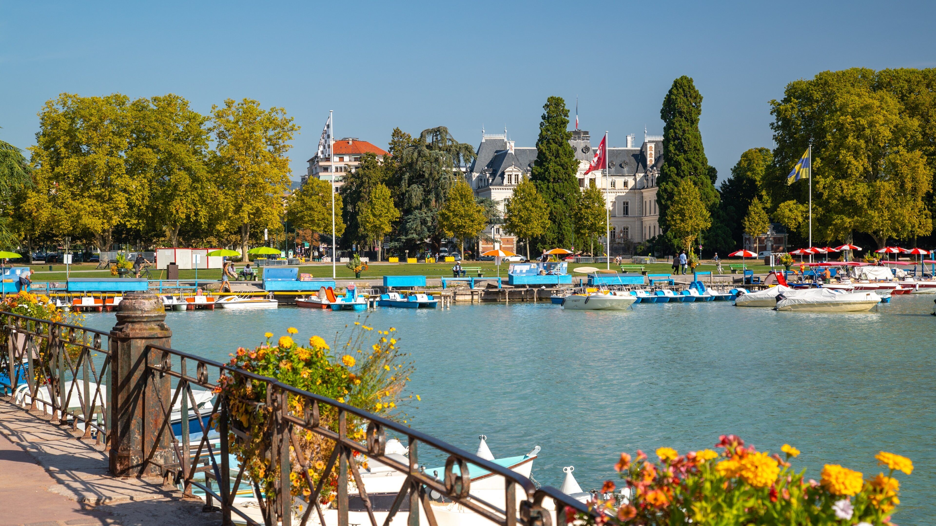 A riverside view with boats docked, a bridge, and a castle in the background.