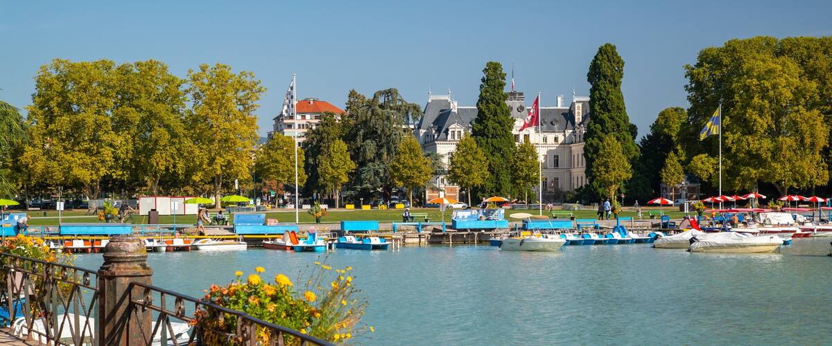 A riverside view with boats docked, a bridge, and a castle in the background.