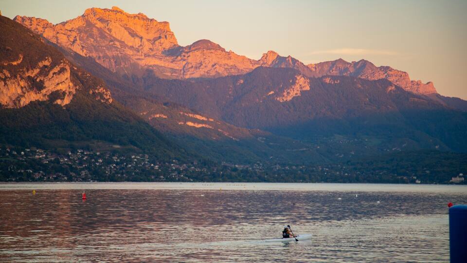 A kayaker on a calm lake with mountains in the background.