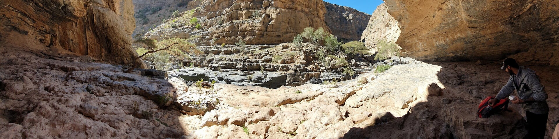 A canyon with a person sitting inside a rock arch.