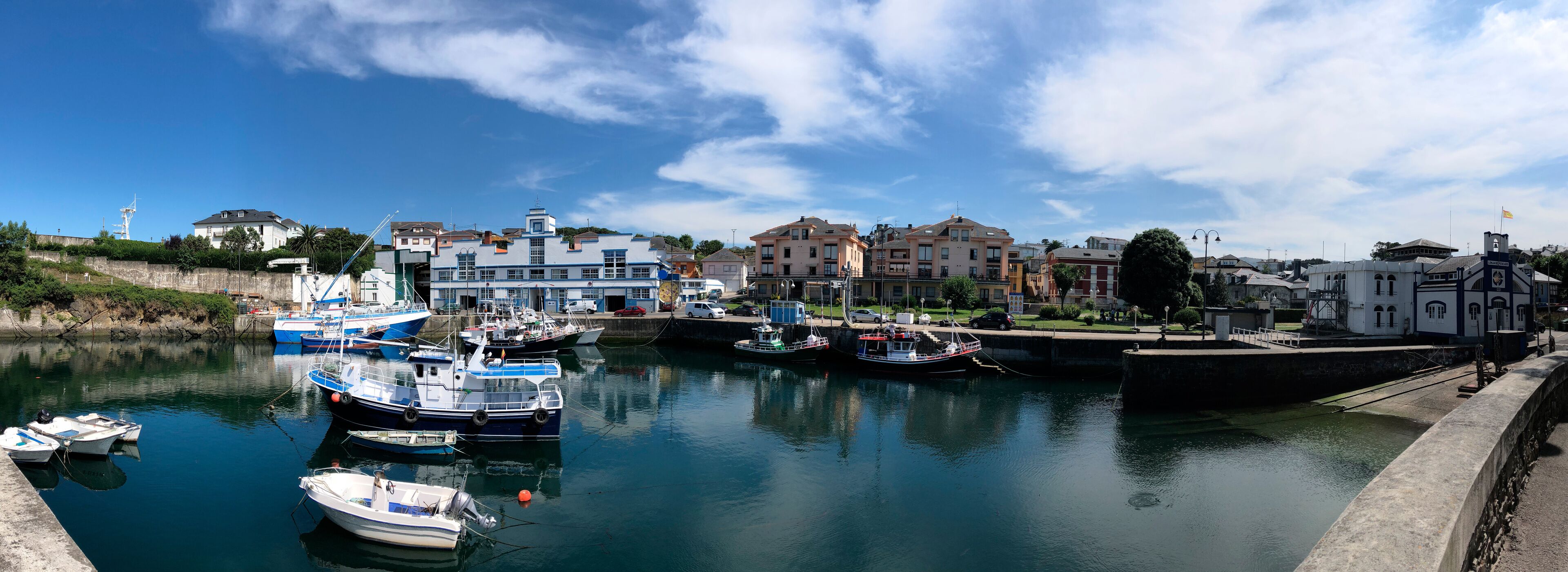A harbor with boats docked, a stone wall, and buildings along the waterfront.